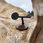 Black metal and wood three-in-one wireless charging stand with circular pads, placed on a large piece of light-colored wood.